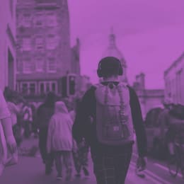 A man wearing headphones walking down a busy street